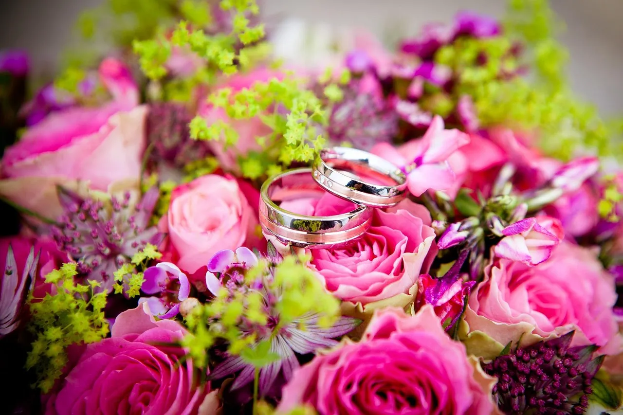 Wedding rings resting among soft white and pink flowers